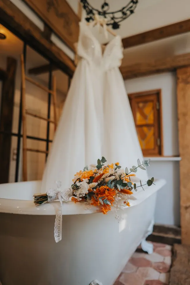 Robe suspendue et bouquet sur une baignoire